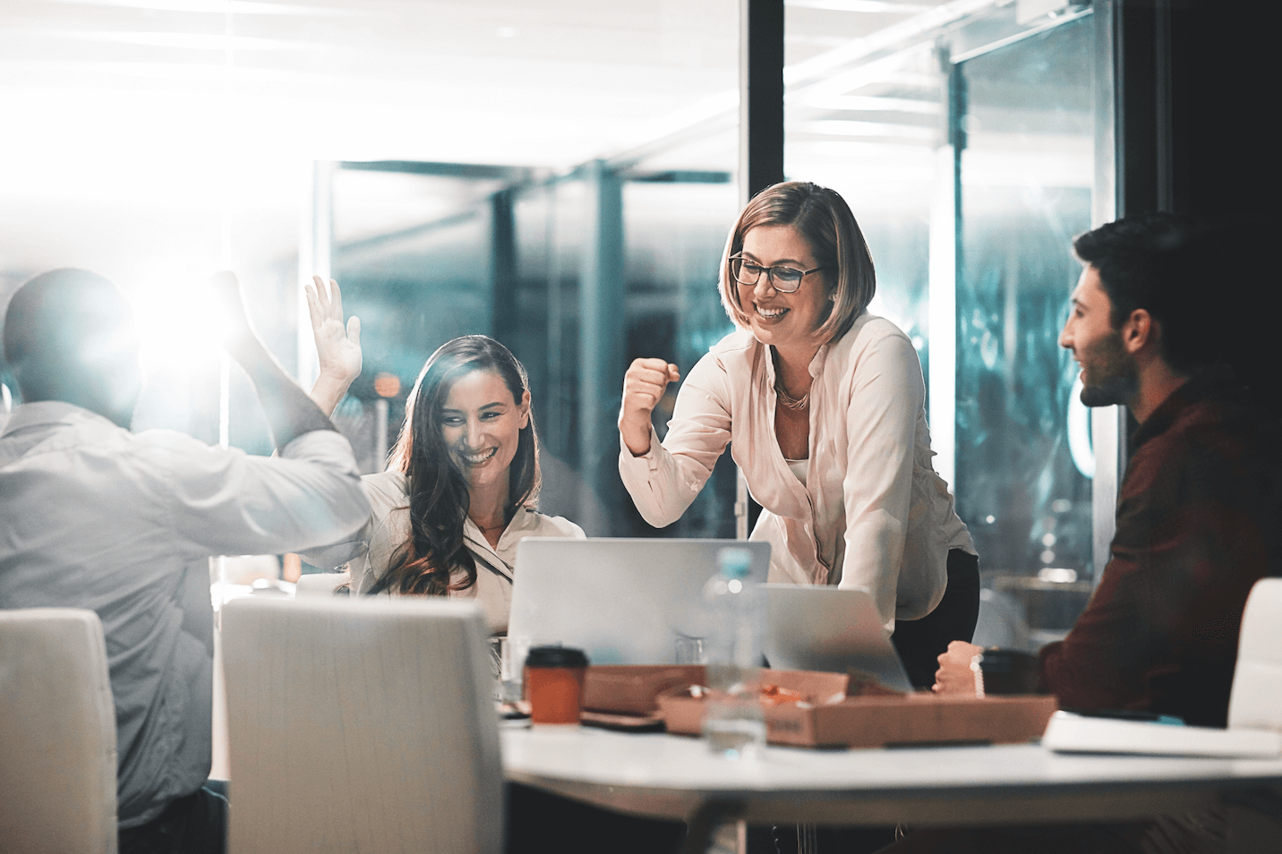 smartly dressed office workers high-fiving in boardroom